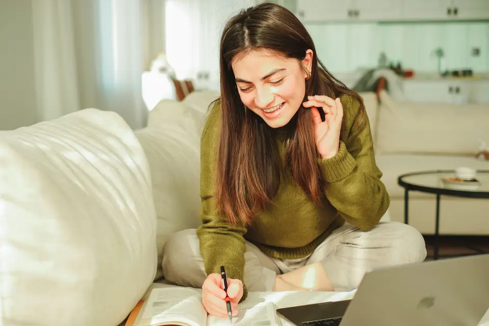 Estudante sorrindo enquanto revisa conteúdos em casa